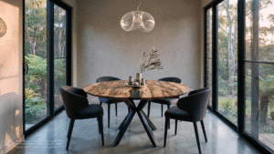 a dining table made by David Suters Timbercraftsman Eumundi from Blackheart Sassafras and chairs in a room with large windows overlooking a tropical bush garden with ferns and gum trees